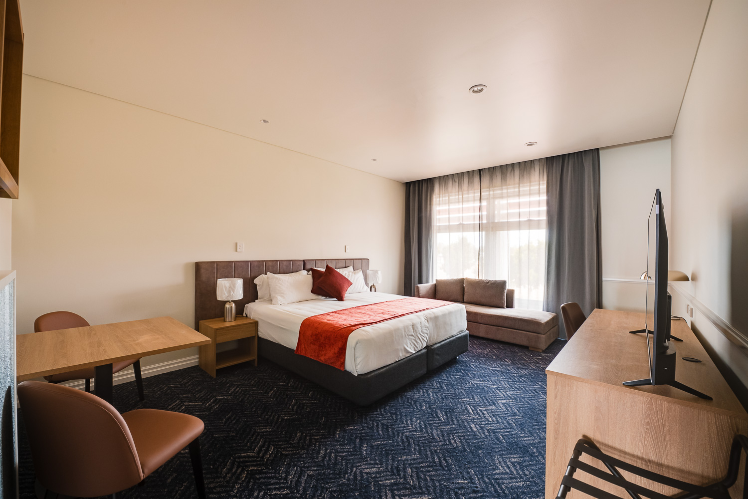 King suite with desk, lounge chair and flat-screen television at Logan Village Hotel Suites