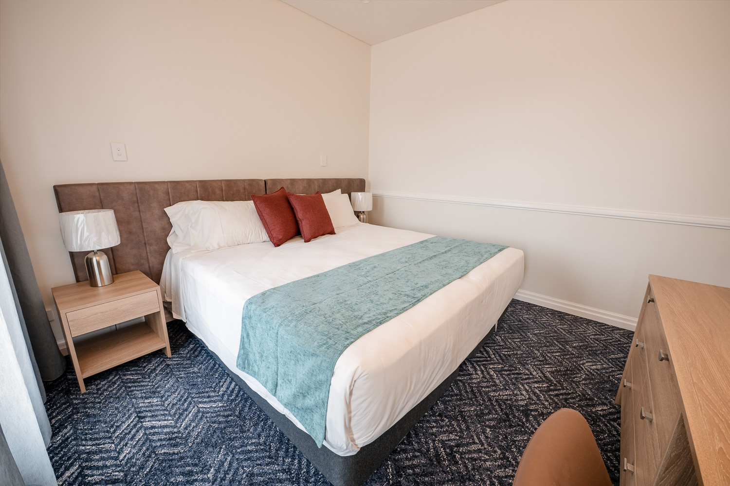 King bed and bedside lighting in a Logan Village Hotel suite