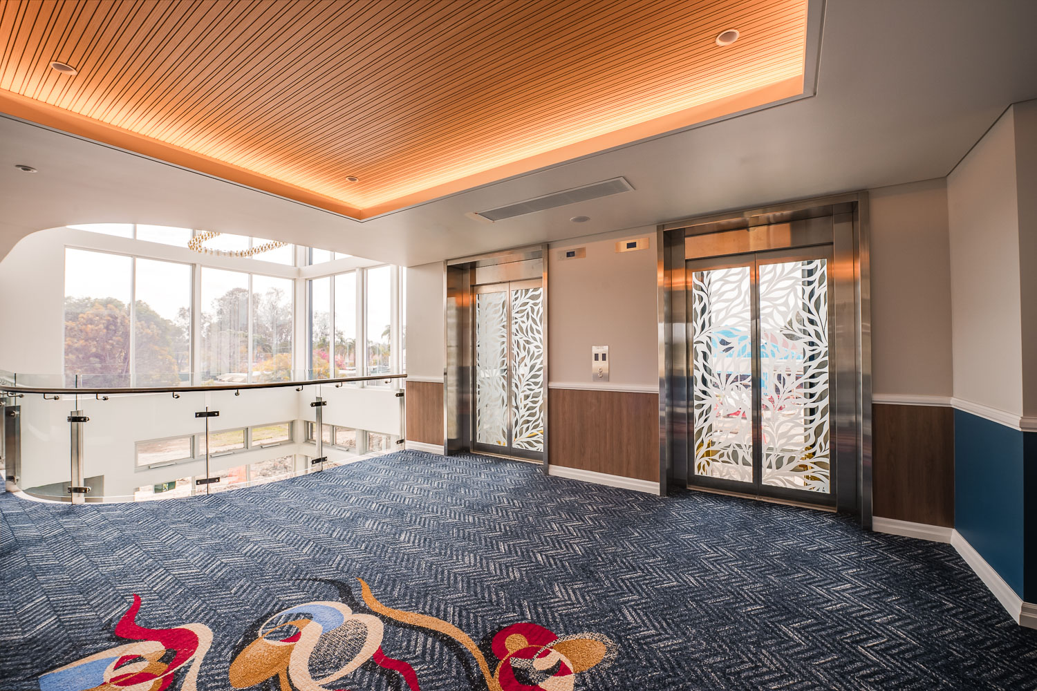 Guest lift lobby with feature ceiling and natural light at Logan Village Hotel Suites