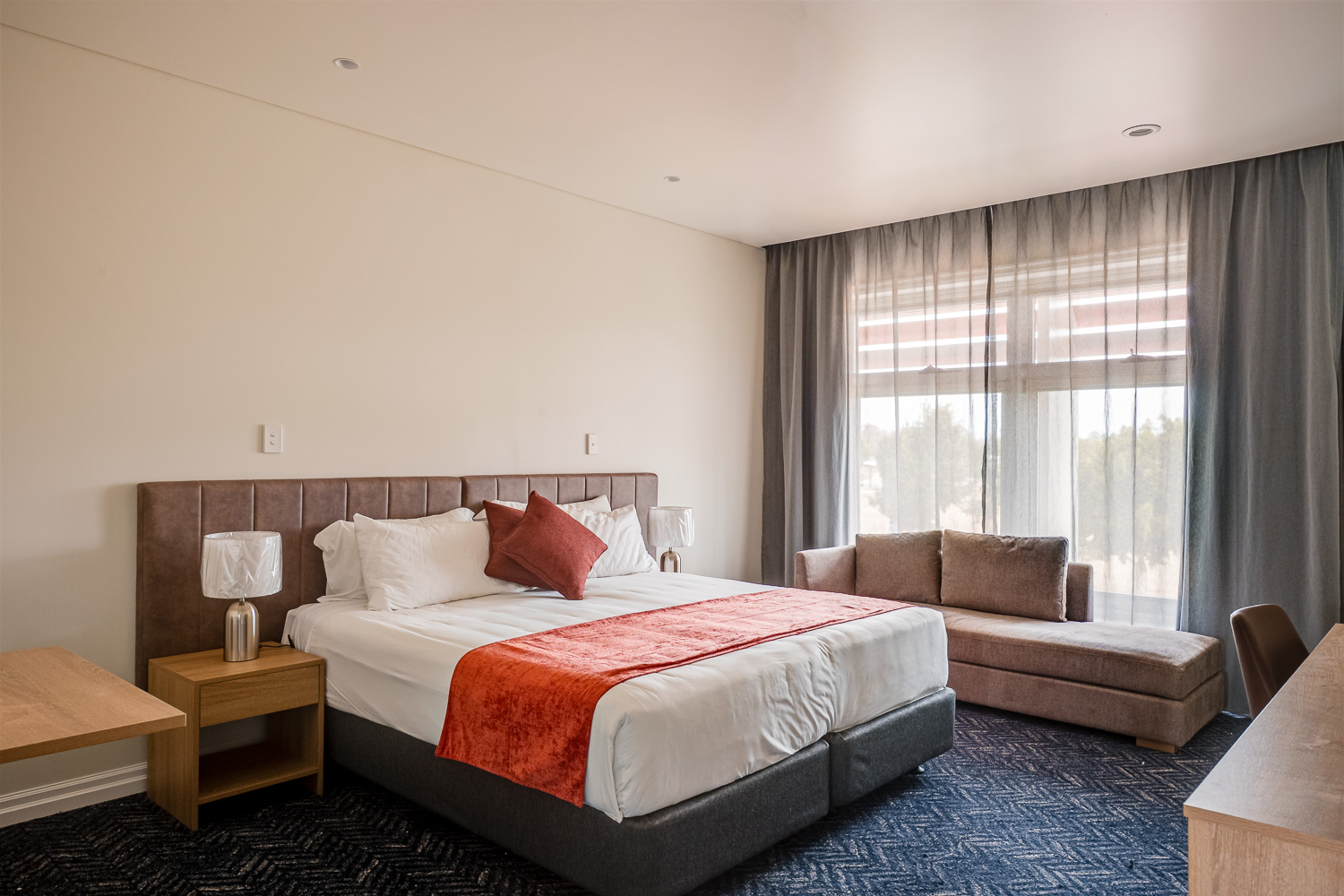 King suite with bed, lounge seating and window at Logan Village Hotel Suites