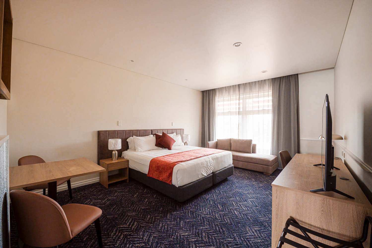 King bed, bedside lamps and flat-screen television in a Logan Village Hotel suite